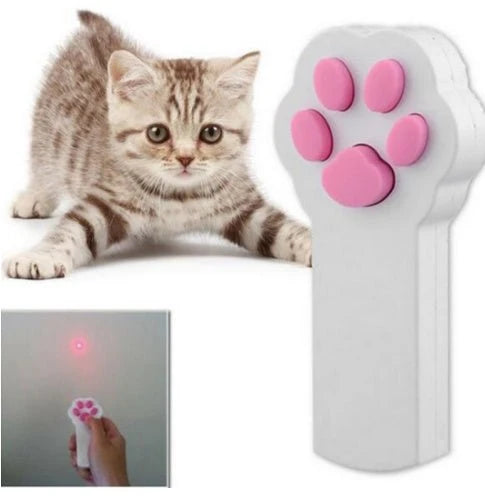 White cat paw shaped laser pointer toy with pink paw print button next to a playful kitten